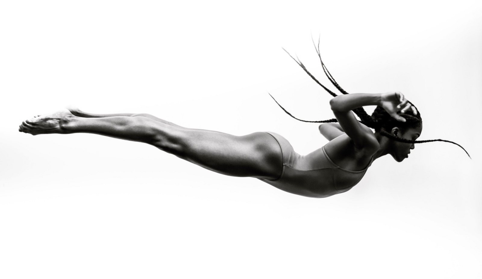 A dancer held perfectly horizontal in mid-air against a plain backdrop