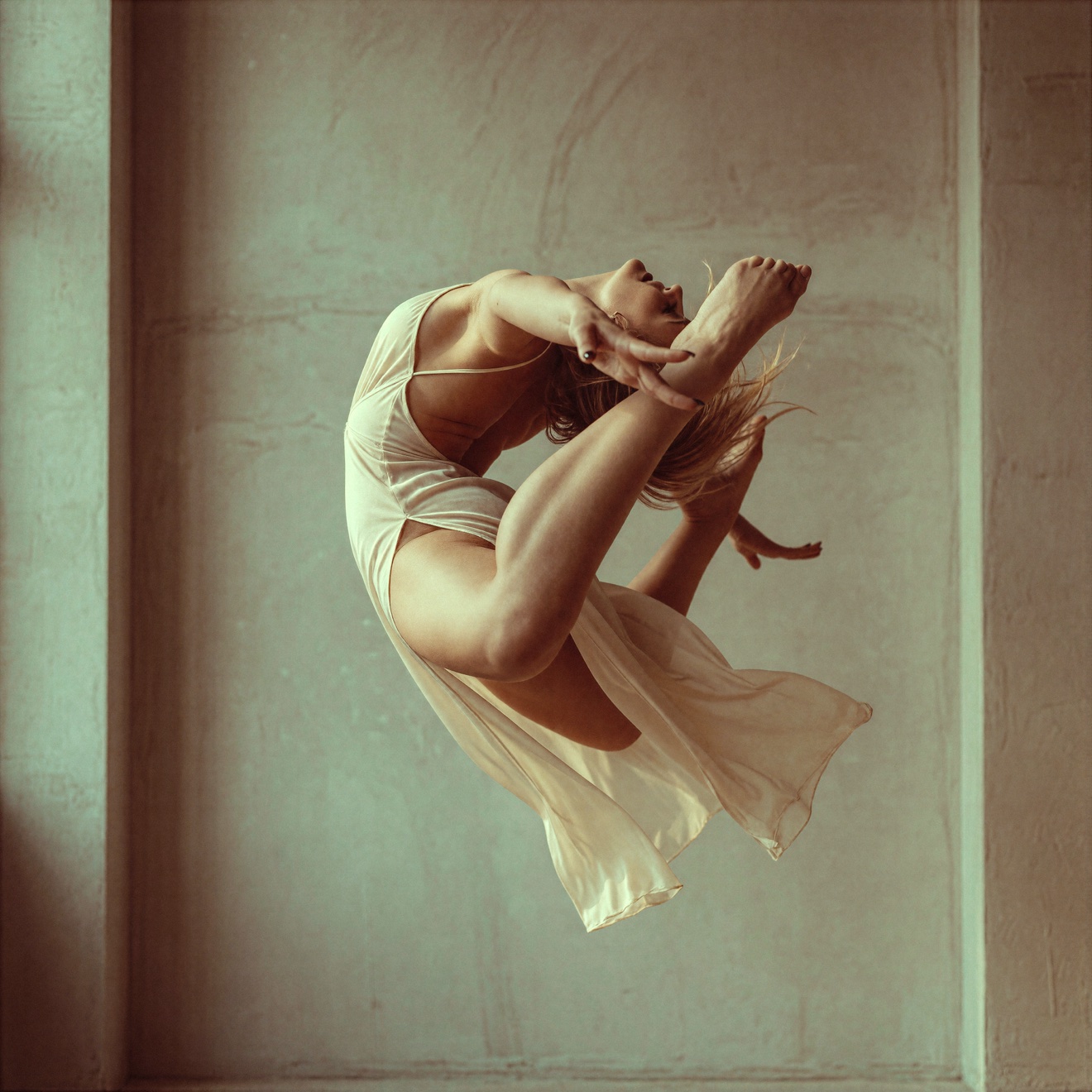A dancer in a white dress caught at the top of a leap